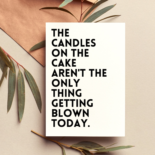 Motivational quote card with text 'The candles on the cake aren't the only thing getting blown today.' surrounded by leaves on a beige background.