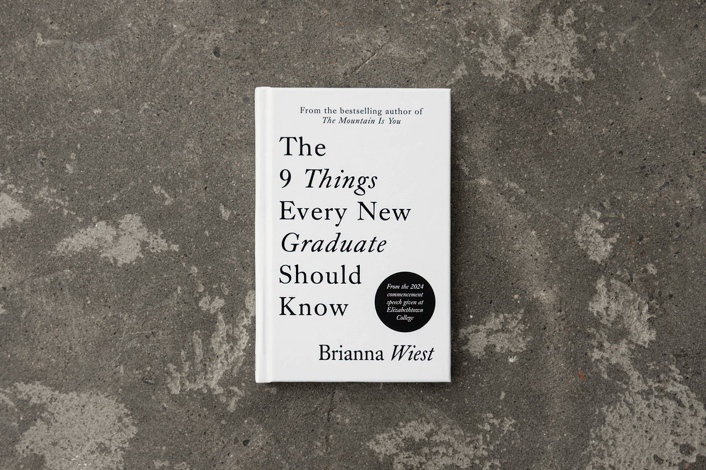 Book titled 'The 9 Things Every New Graduate Should Know' by Brianna Wiest on a textured gray surface
