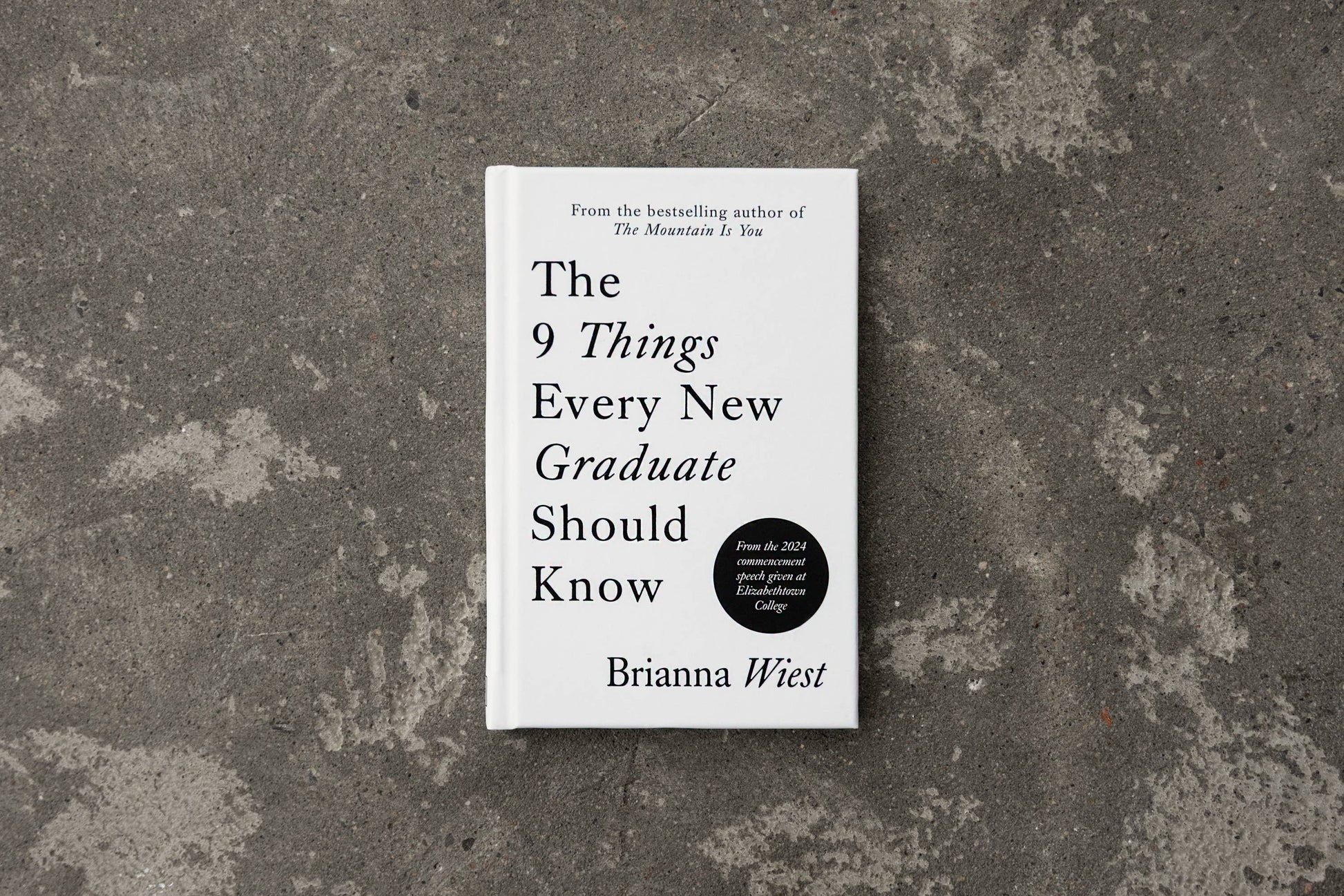 Book titled 'The 9 Things Every New Graduate Should Know' by Brianna Wiest on a textured gray surface