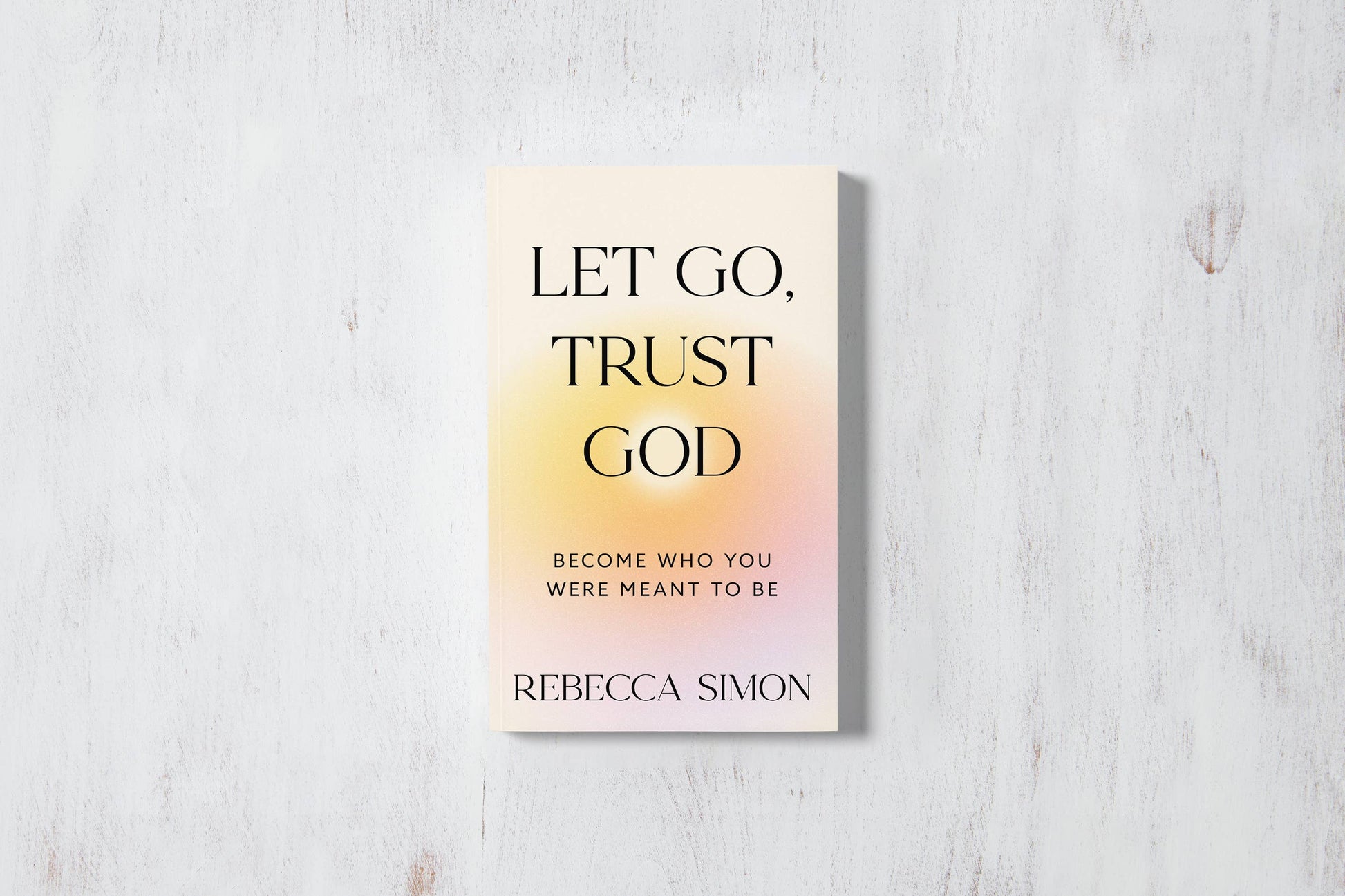 Book titled 'Let Go, Trust God' by Rebecca Simon on a light wooden surface
