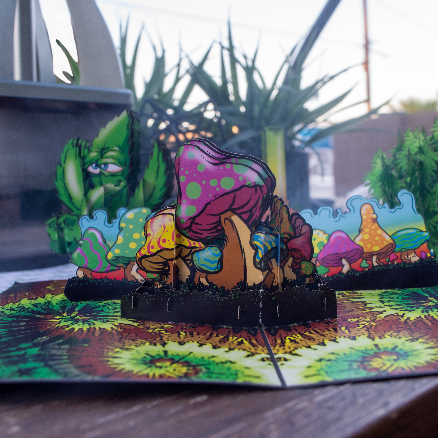 Colorful mushroom creature figurine on a tie-dye surface with outdoor background