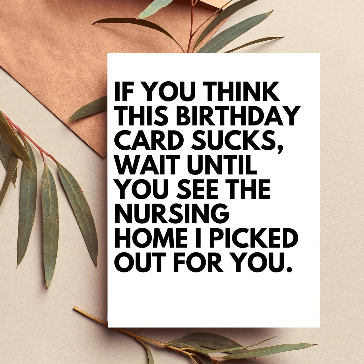 Birthday card with humorous text on a beige background with green leaves